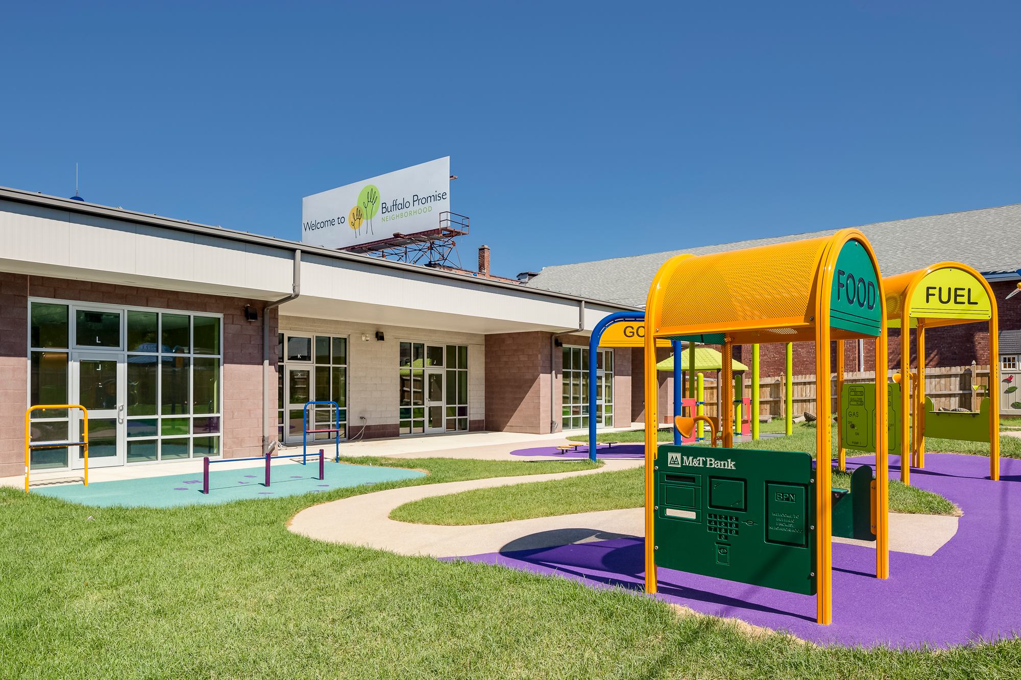 Buffalo Promise Neighborhood school courtyard playground with colorful play structures and a brick building